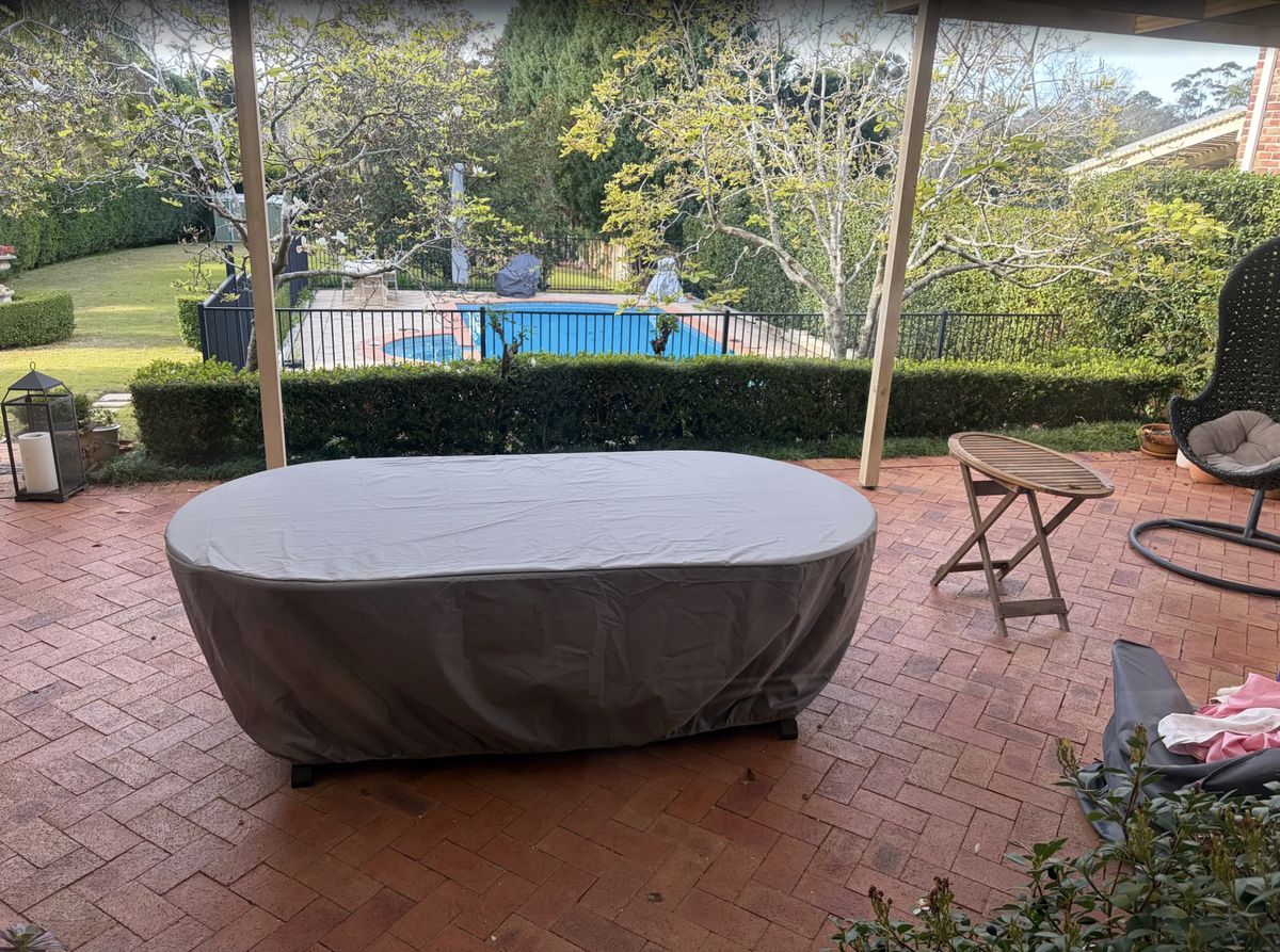 Custom made oval outdoor table cover in grey fitted on a patio table – The Cover Company Australia