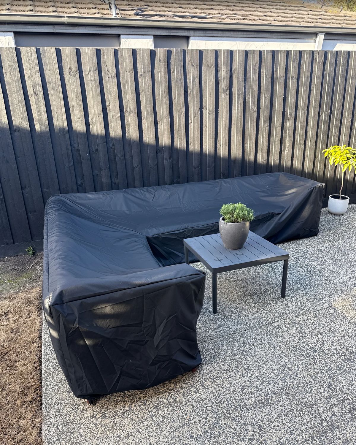 Custom made outdoor lounge cover in black fitted over an L-shaped outdoor lounge – The Cover Company Australia